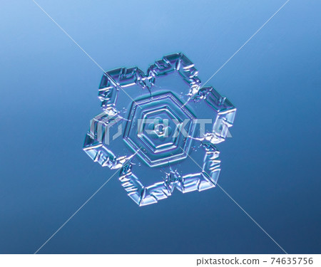 Snowflake on smooth gradient background. Macro photo of real snow crystal on glass surface. This is small snowflake with unusual pattern. Snowflake on smooth gradient background. Macro photo of real snow crystal on glass surface. This is small snowflake with unusual pattern. 74635756