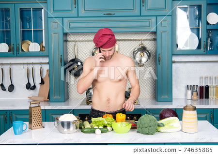 Man talk on mobile phone in kitchen. Cook in chef hat Man talk on mobile phone in kitchen. Cook in chef hat 74635885