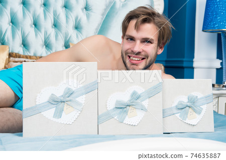 Macho smile with present boxes on bed in bedroom 74635887