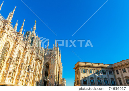 Famous church Milan Cathedral Duomo di Milano with Gothic spires and white marble statues. Top tourist attraction on piazza in Milan Lombardia Italy. Wide angle view of old Gothic architecture and art 74636917