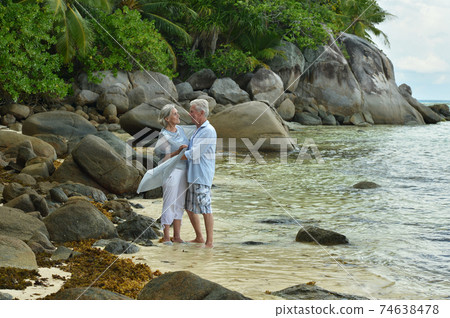 Happy elderly couple dancing on tropical beach Happy elderly couple dancing on tropical beach 74638478