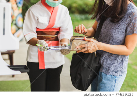 Woman waitress in medical mask receiving credit card from customer. 74639125