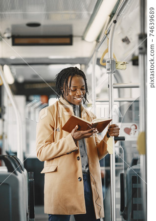 Young African businessman standing on a bus Young African businessman standing on a bus 74639689