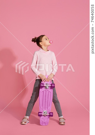 child girl with chewing gum holding skateboard 74640058