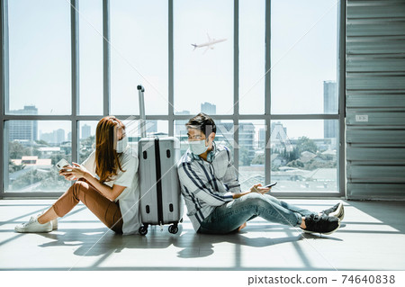 Couple asian traveler looking smartphone and sit waiting for flight at airport terminal. 74640838