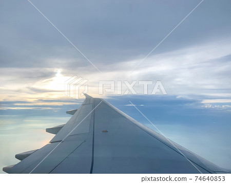 Wing of an airplane flying above in the evening 74640853