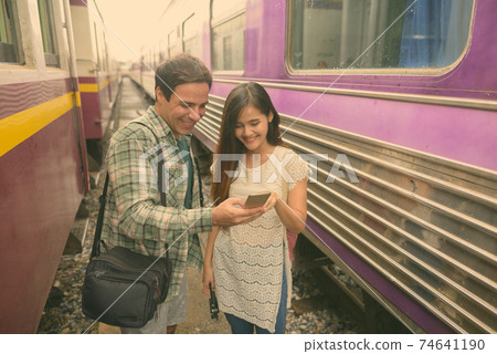 Persian tourist man and young Asian tourist woman together at the railway station Persian tourist man and young Asian tourist woman together at the railway station 74641190