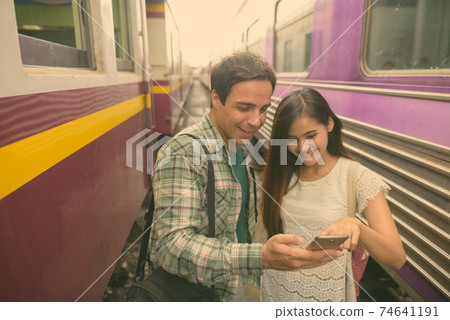 Persian tourist man and young Asian tourist woman together at the railway station 74641191