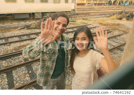 Persian tourist man and young Asian tourist woman together at the railway station Persian tourist man and young Asian tourist woman together at the railway station 74641192