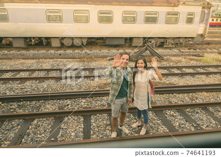 Persian tourist man and young Asian tourist woman together at the railway station Persian tourist man and young Asian tourist woman together at the railway station 74641193