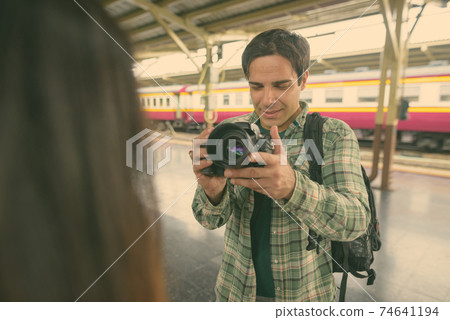 Persian tourist man and young Asian tourist woman together at the railway station Persian tourist man and young Asian tourist woman together at the railway station 74641194