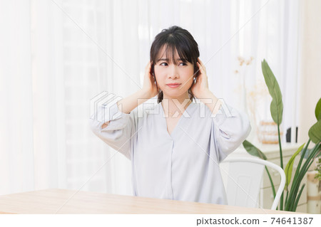 做一個手勢，閉上她的耳朵的年輕女子 74641387