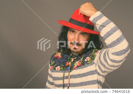 Handsome man with curly hair and mustache against gray background Handsome man with curly hair and mustache against gray background 74641618