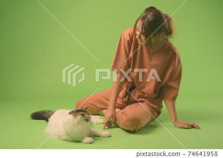 Studio shot of young beautiful woman against green background 74641958