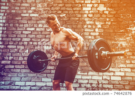 Athletic man working out with a barbell. Strength and motivation Athletic man working out with a barbell. Strength and motivation 74642876
