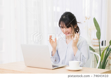 A young woman surprised while using a laptop in the room A young woman surprised while using a laptop in the room 74643410