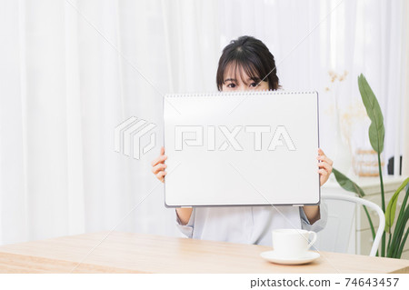 Young woman with a large sketchbook in the room Young woman with a large sketchbook in the room 74643457