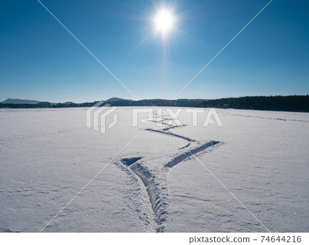 Amazing cutouts of ice skater tracks in dusty snow. View of open frozen lake or pond Amazing cutouts of ice skater tracks in dusty snow. View of open frozen lake or pond 74644216