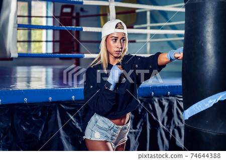 Concentrated woman doing a fitness boxing workout with a punchin Concentrated woman doing a fitness boxing workout with a punchin 74644388