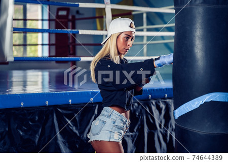 Concentrated woman doing a fitness boxing workout with a punchin Concentrated woman doing a fitness boxing workout with a punchin 74644389