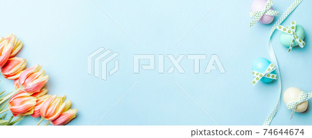 Easter border. Colorful egg with tape ribbon, spring tulips, feathers on pastel blue background in Happy Easter decoration. Banner, top view. Easter border. Colorful egg with tape ribbon, spring tulips, feathers on pastel blue background in Happy Easter decoration. Banner, top view. 74644674