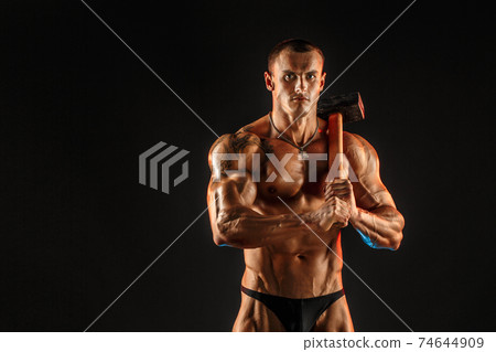Portrait of shirtless athlete with hammer on shoulder 74644909