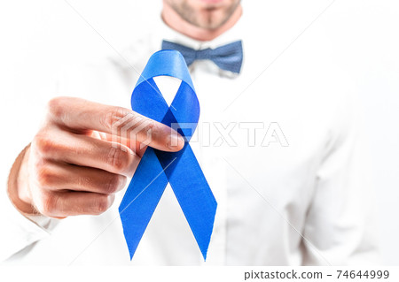 Prostate care. Awareness prostate of men health in November. Hipster men in bright shirt, cyan bowtie with blue ribbon in hands on white background. World cancer day and world diabetes day concept. Prostate care. Awareness prostate of men health in November. Hipster men in bright shirt, cyan bowtie with blue ribbon in hands on white background. World cancer day and world diabetes day concept. 74644999
