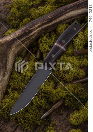 Hunting knife made of damascus steel on wooden background Hunting knife made of damascus steel on wooden background 74645218