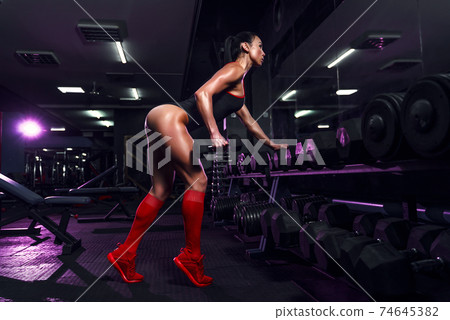 Attractive fit sexy woman in the gym crouches with a barbell. Wo 74645382