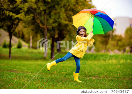 Happy funny child girl with multicolor umbrella in rubber boots at autumn park Happy funny child girl with multicolor umbrella in rubber boots at autumn park 74645487