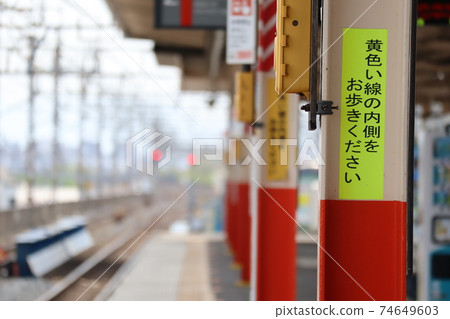 Station platform with the notation "Please walk inside the yellow line" 74649603