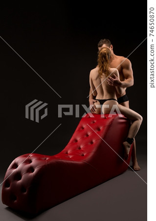 unrecognize sexy couple during hot foreplay on red bdsm sofa unrecognize sexy couple during hot foreplay on red bdsm sofa 74650870