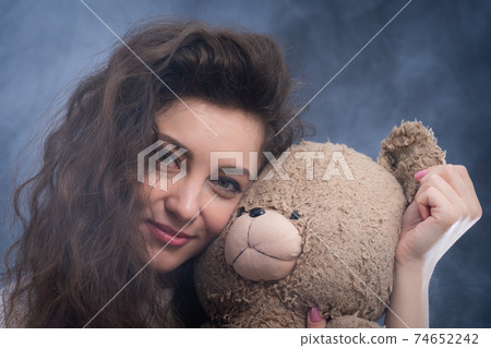 cheerful curly young woman holding teddy bear. concept of present and happiness cheerful curly young woman holding teddy bear. concept of present and happiness 74652242