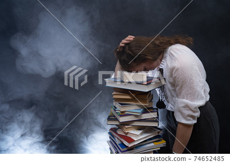 Sad female student reading with lots of books for the exam. Concept homeschooling Sad female student reading with lots of books for the exam. Concept homeschooling 74652485