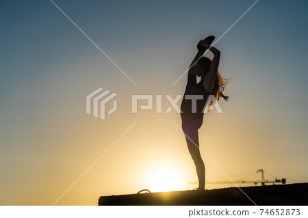 Female dancer on the edge of rooftop on the sky background. Concept of healthy lifestyle, talent and aspiration Female dancer on the edge of rooftop on the sky background. Concept of healthy lifestyle, talent and aspiration 74652873