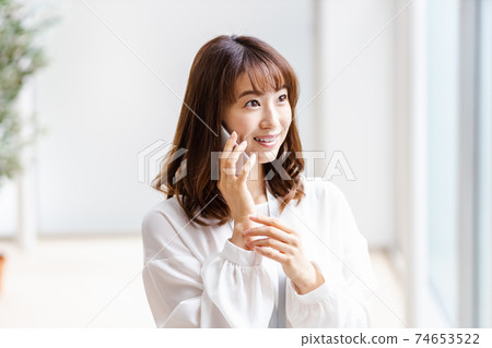 A woman who puts her smartphone on her ear and smiles 74653522