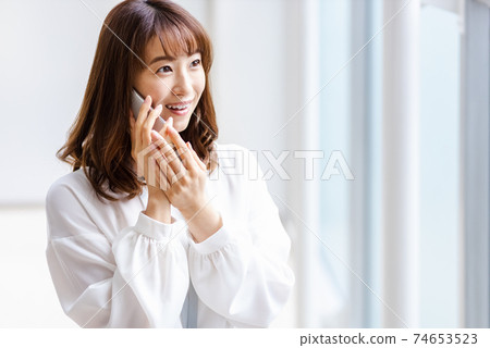 一個將智能手機放在耳朵上並微笑的女人 74653523