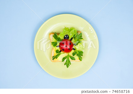 Fun food art for kids. Ladybug sandwich on blue background. How to make creative breakfast for kid at home. Step by step instruction, view from above. Step 1 of . Fun food art for kids. Ladybug sandwich on blue background. How to make creative breakfast for kid at home. Step by step instruction, view from above. Step 1 of . 74658716