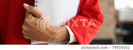 Woman in red suit is holding workbook Woman in red suit is holding workbook 74659102