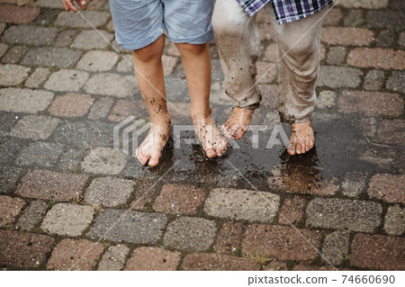 photo of two barefoot boys playing in mud 74660690