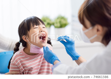 doctor checking throat of girl 74661386