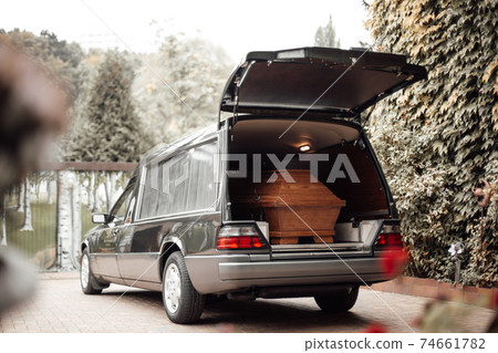 wooden coffin in the back of a car at the crematory 74661782