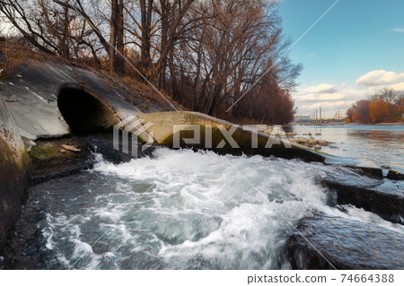 Large sewage tunnel with filth flowing out 74664388