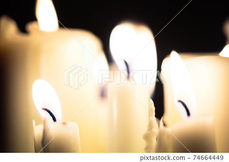 Candles glowing against dark background Candles glowing against dark background 74664449