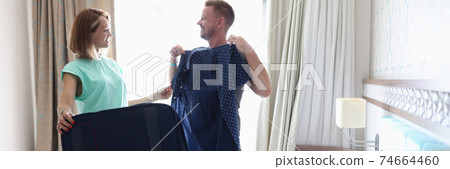 Man try on female jacket with polka dots in room. 74664460