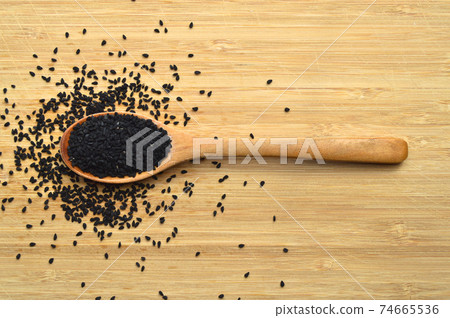 Dry black cumin in wooden spoon, on bamboo cutting board Dry black cumin in wooden spoon, on bamboo cutting board 74665536