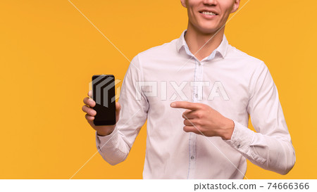 Excited winner Asian man pointing at mobile phone Excited winner Asian man pointing at mobile phone 74666366