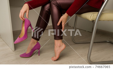 Woman suffering from leg pain in office. Woman suffering from leg pain in office. 74667065