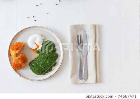 Cannelloni stuffed with spinach, feta cheese and cashew nuts with tomato and garlic sauce, embellished with parmesan cheese shavings and basil leaves. All on white wooden table background. 74667471