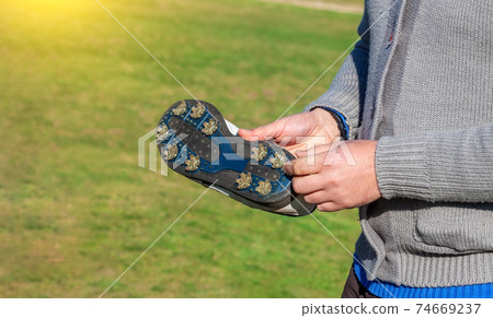 Close up of a golfer showing a a golf shoe with spikes to help adhere to the grass field. Golf footwear. Close up of a golfer showing a a golf shoe with spikes to help adhere to the grass field. Golf footwear. 74669237